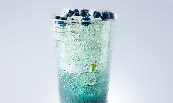 Blue sparkling citrus drink topped with blueberries in a clear cup